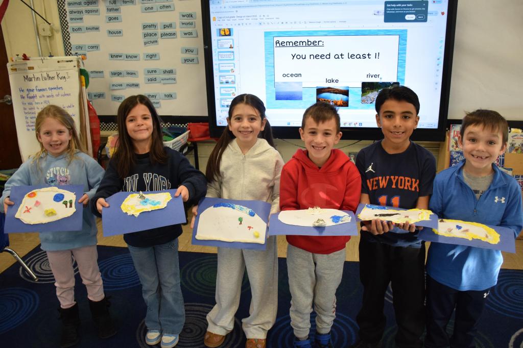 kids holding land projects standing in front of screen